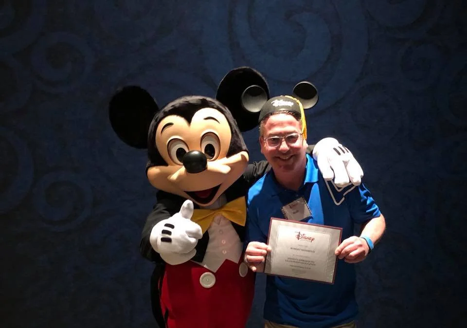 Rob accepts his Disney Institute diploma from … do we really have to identify this beloved character?