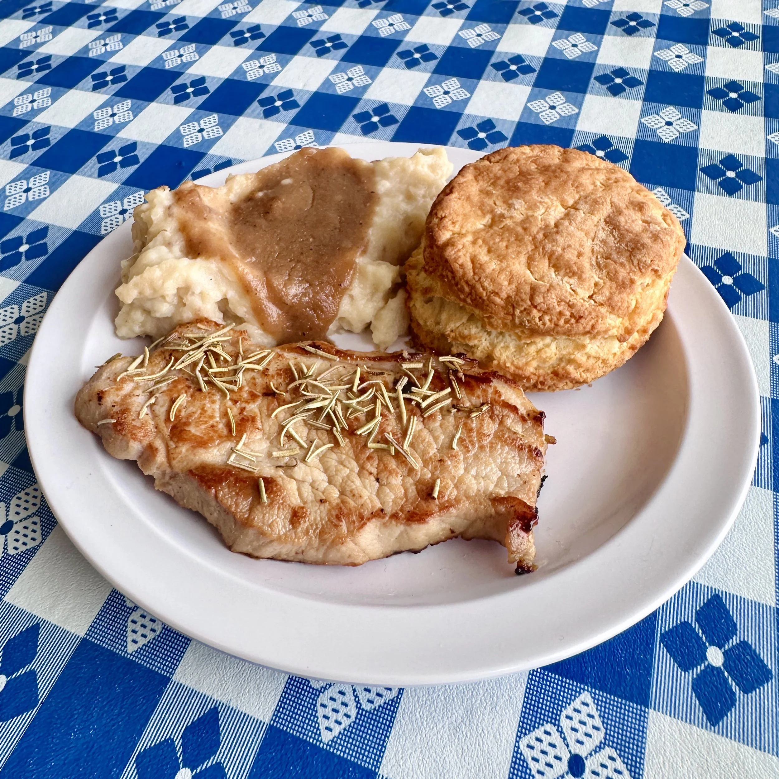Rosemary grilled pork chop served with a biscuit and a side