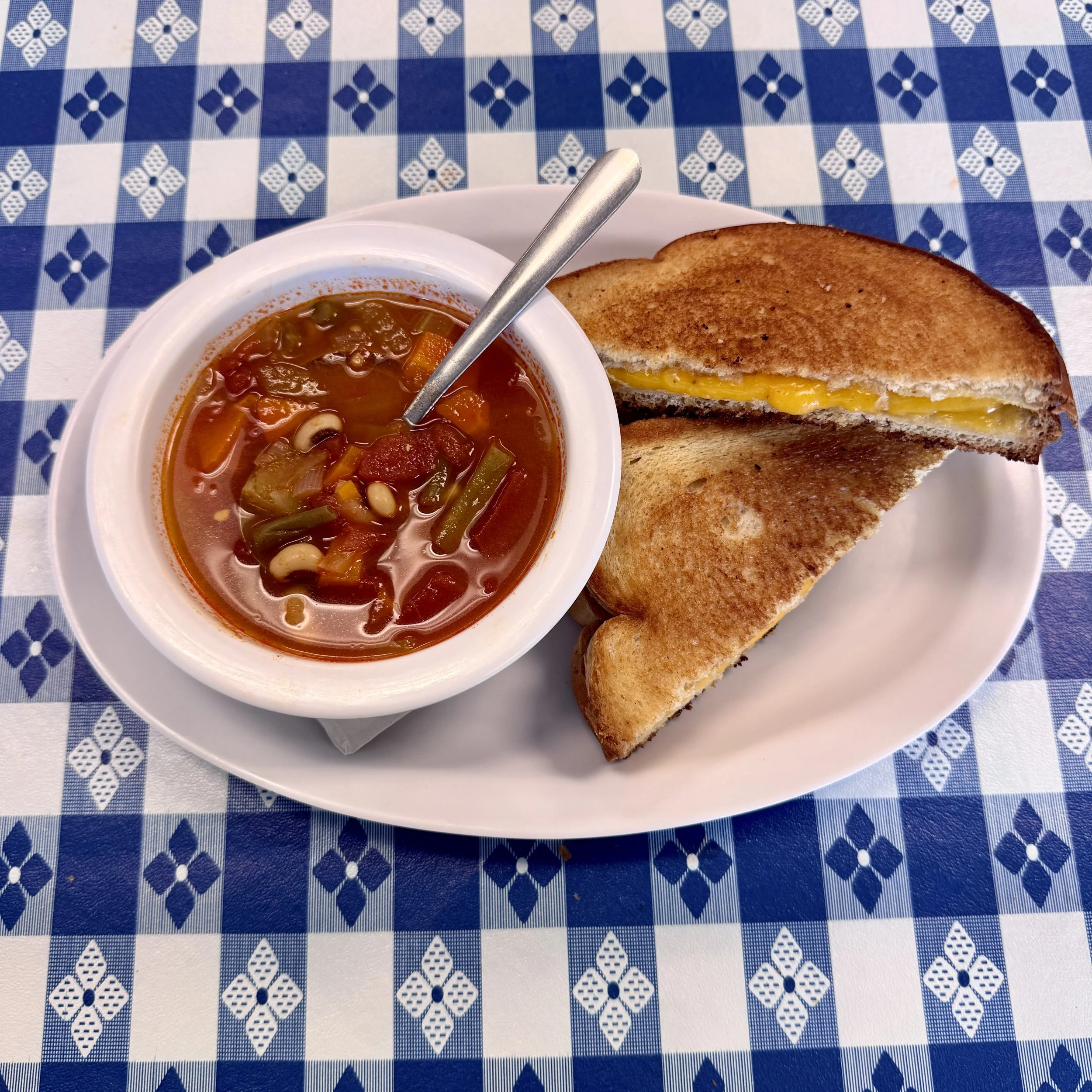 owl of soup with a grilled cheese sandwich cut in half.