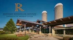 Winthrop Rockefeller Institute building with cylindrical silos and modern entrance under a clear blue sky.