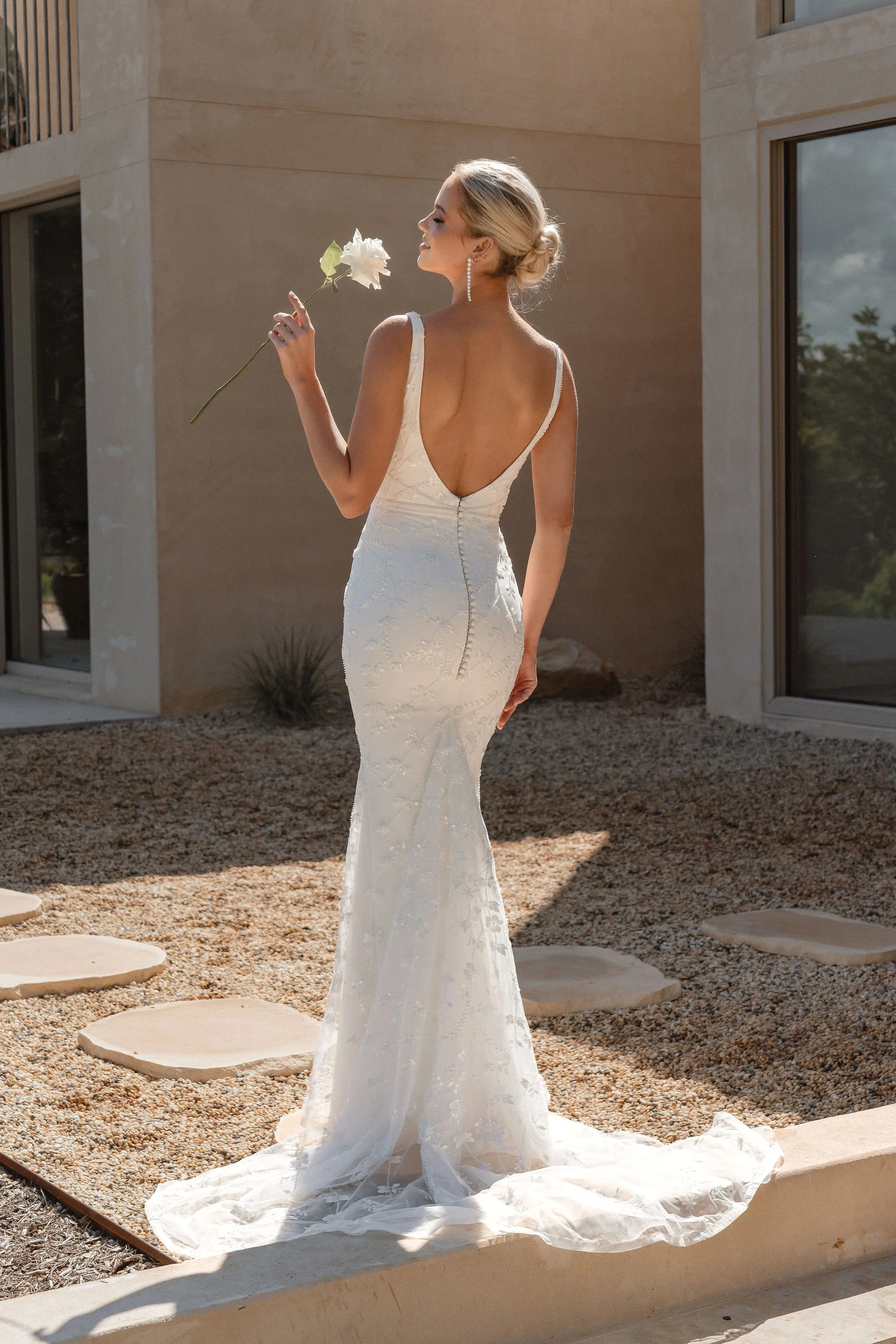 A bride is romantically holding a white roses as she poses on the beautiful country side of Byron Bay, the bridal moment is capture by wedding photographer Nathan Lapham.