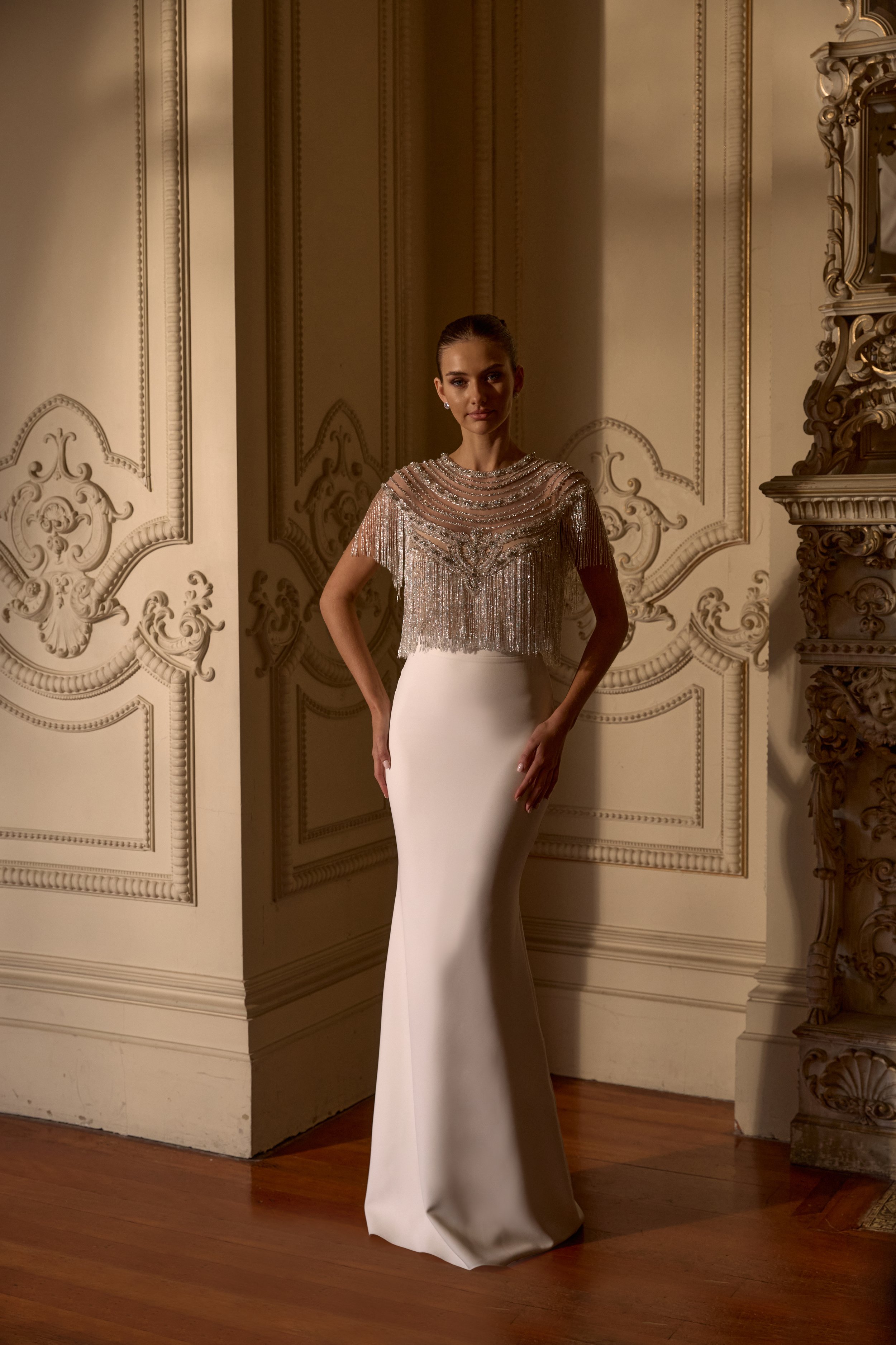 Glamour meets sophistication in the Giselle topper, adorned with vintage-toned embellishments and dramatic fringing. Paired with a fitted bridal skirt for a sleek, show-stopping bridal ensemble.