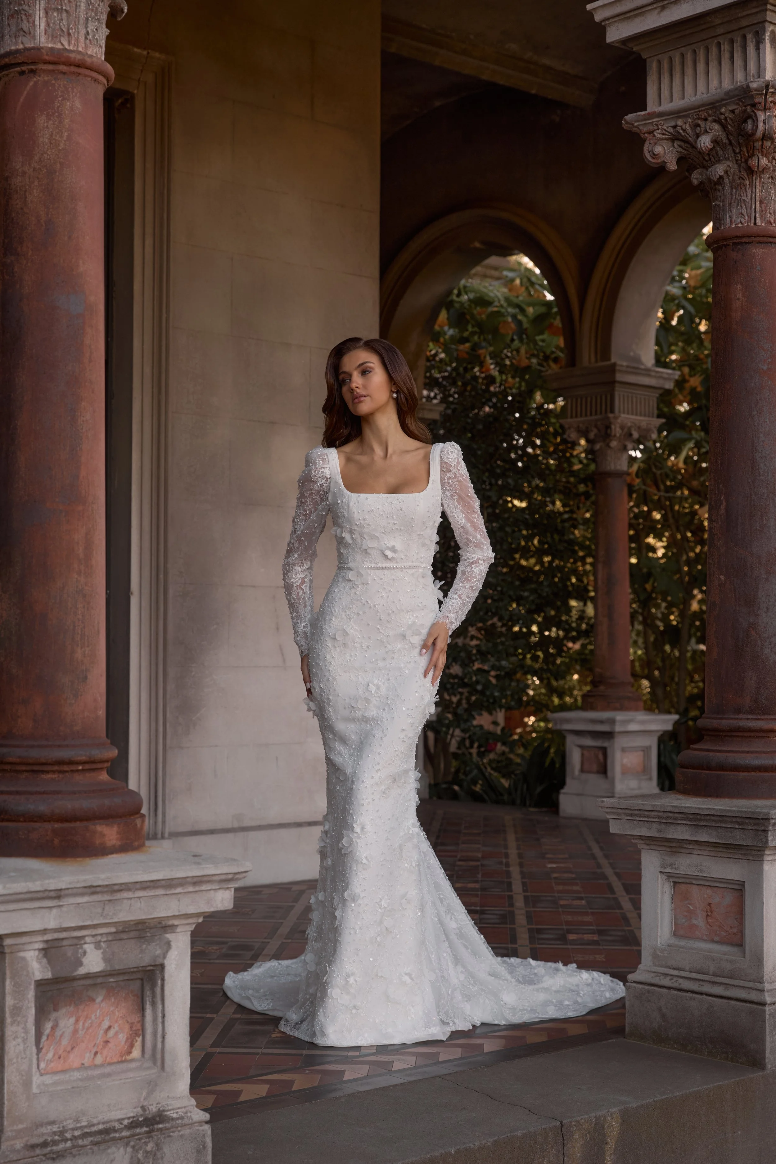 Hand-embellished James bridal gown with delicate beaded lace, 3D florals, and a flattering square neckline, available with cap or long sleeves in soft ivory or latte hues.