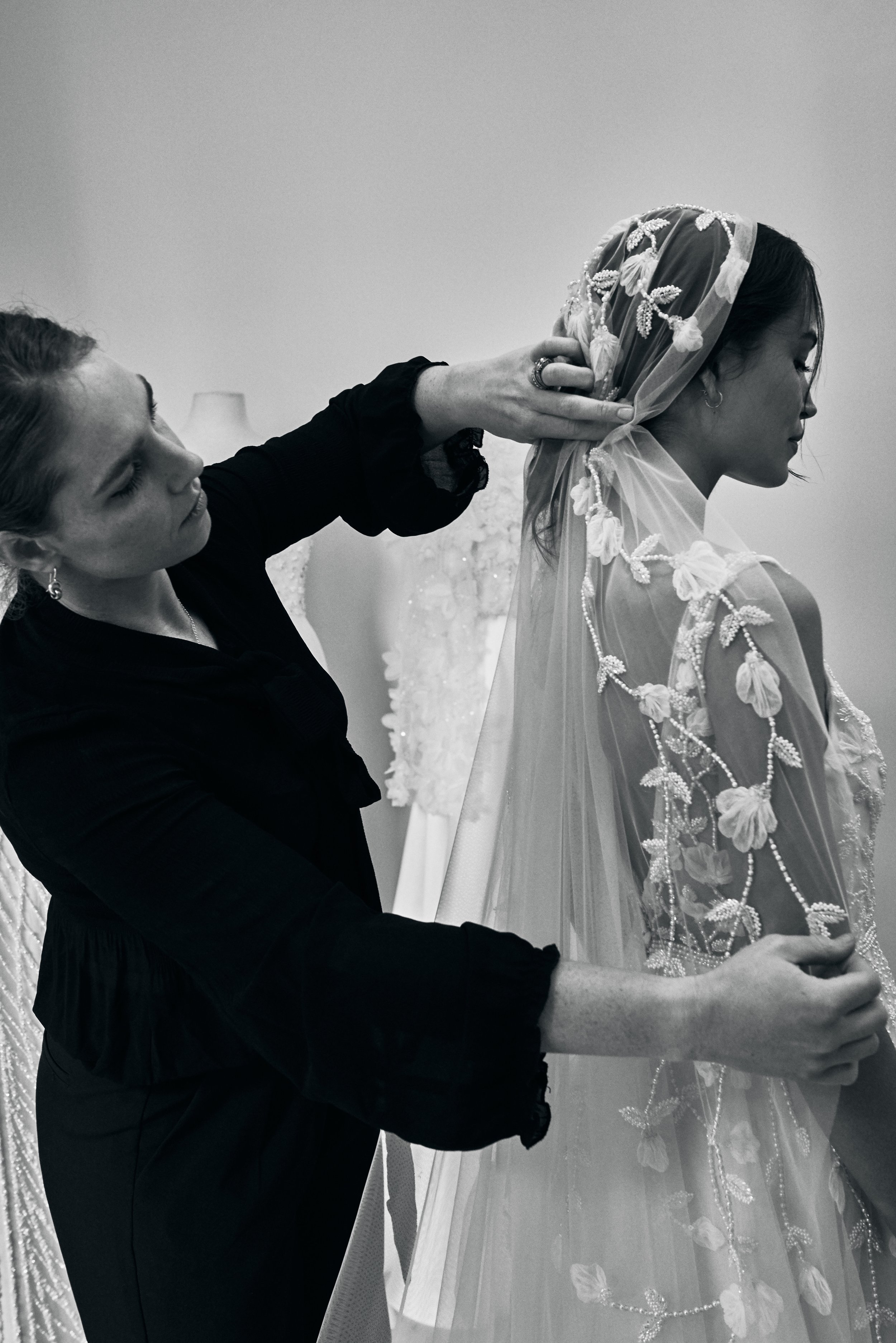 Uncover the creation process of the Iris Veil. Learn about the meticulous hand-beading and exquisite lace work that make this veil a timeless bridal accessory.