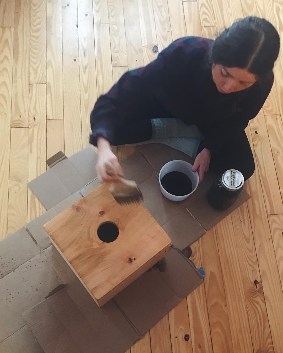 Me applying homemade black walnut stain to each stool