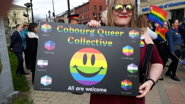 Organizer Ashley Bouman with a poster that shows variations on the Pride flag