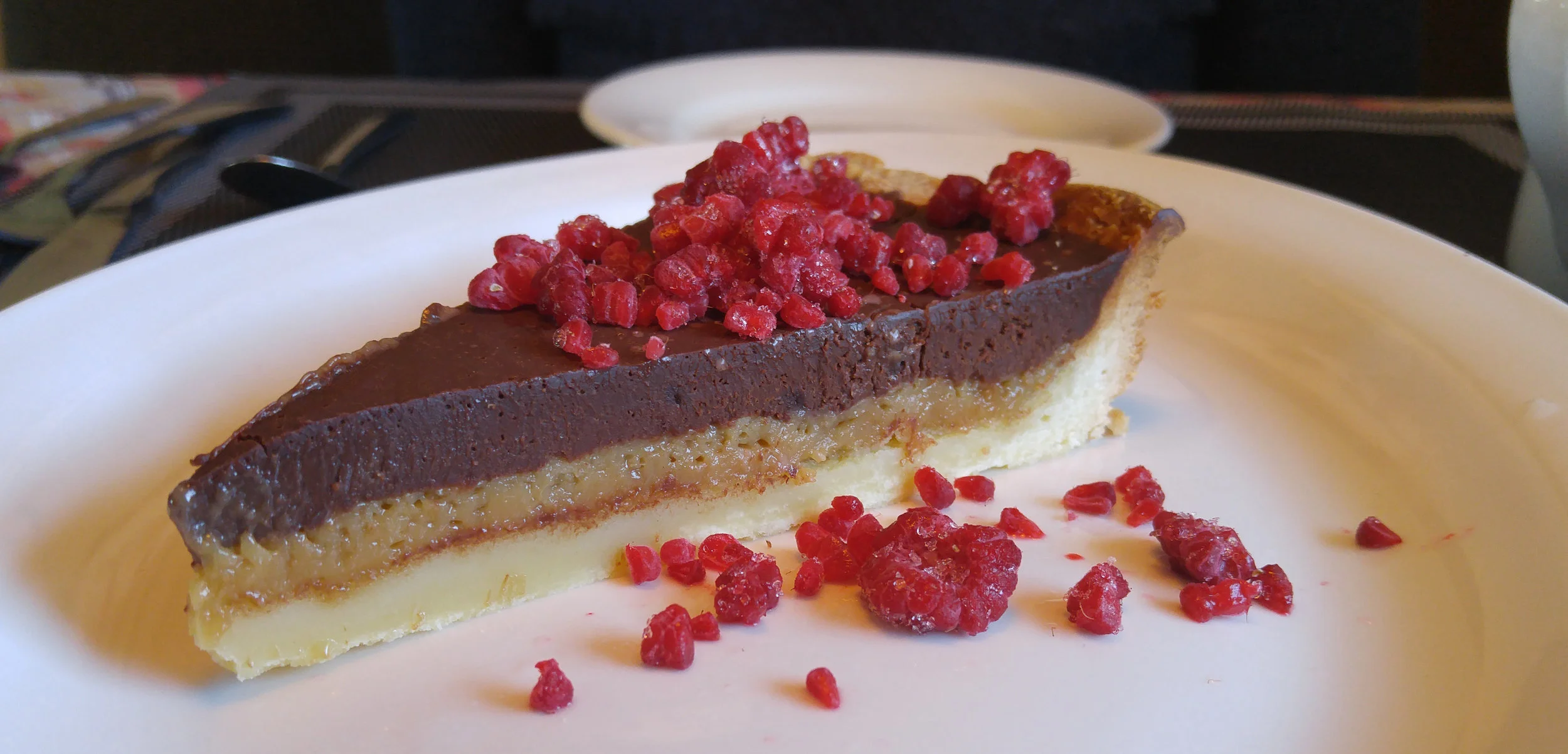 A maple tart with chocolate ganache and raspberry crumbs.