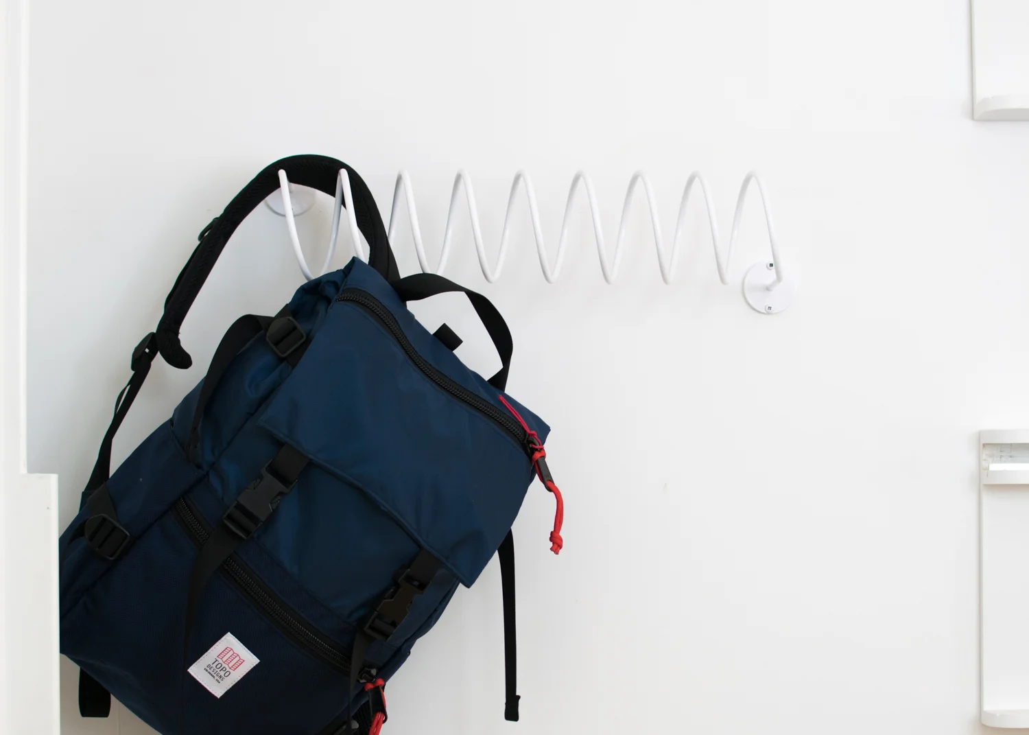 This That's Corkscrew Wall Hook holding a backpack.