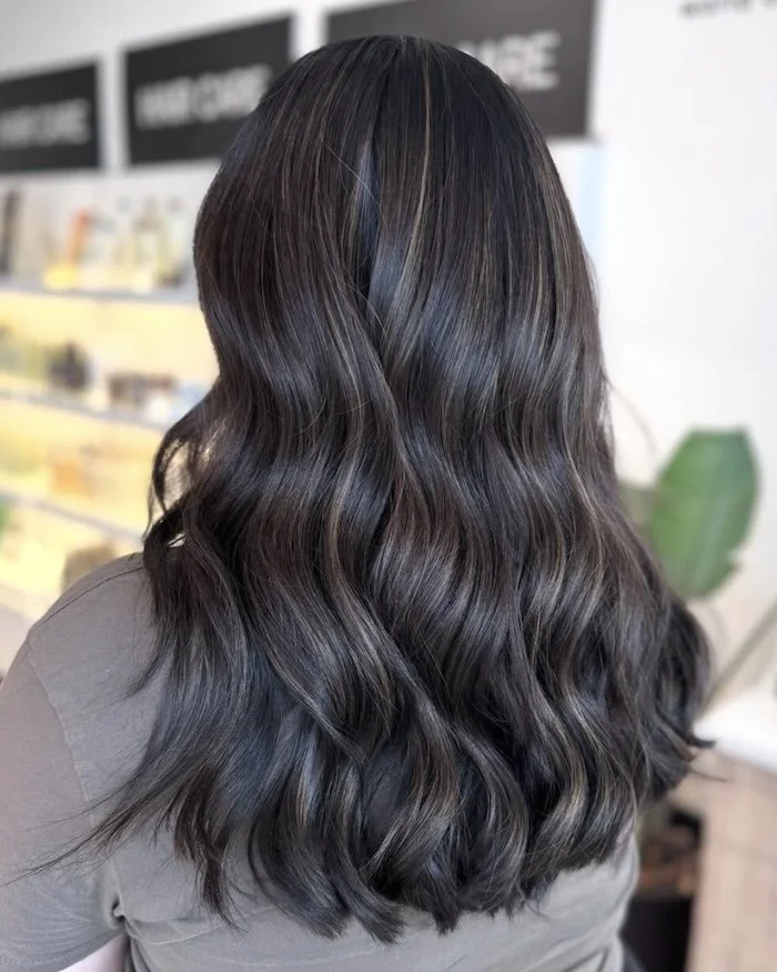 Back view of a woman with long, wavy, dark brown hair.