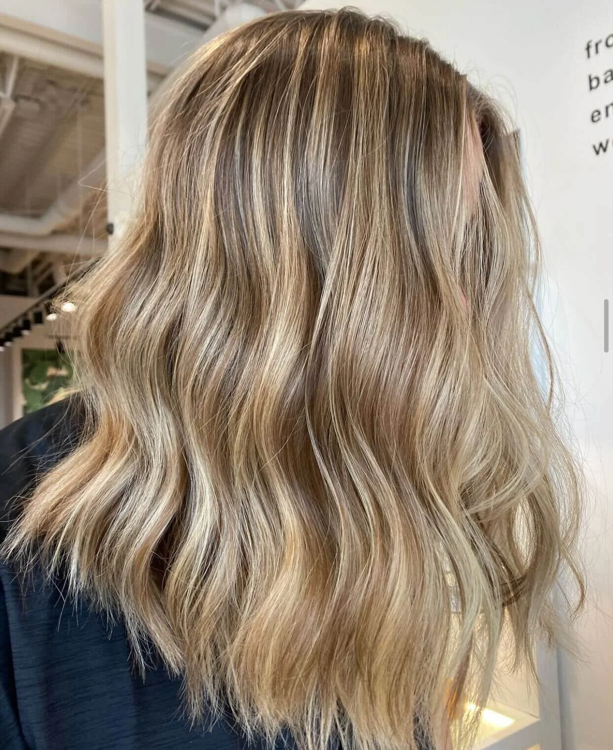 Close-up of blonde wavy hair styled with loose curls in a salon.