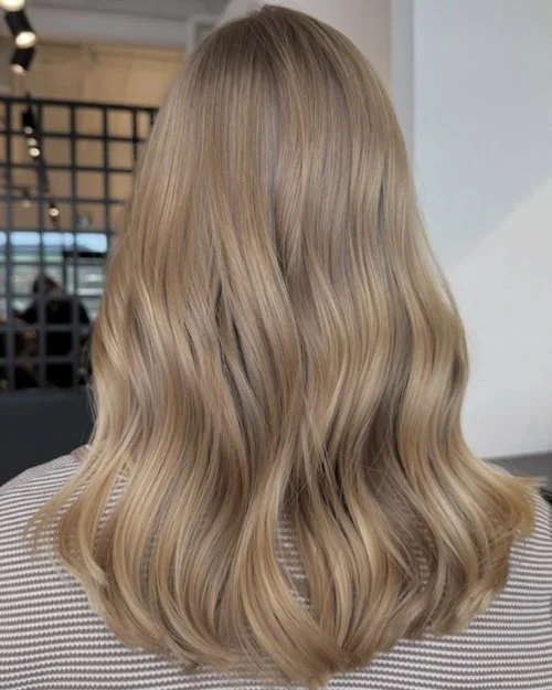 Back of a woman with shoulder-length blonde hair styled in loose waves.