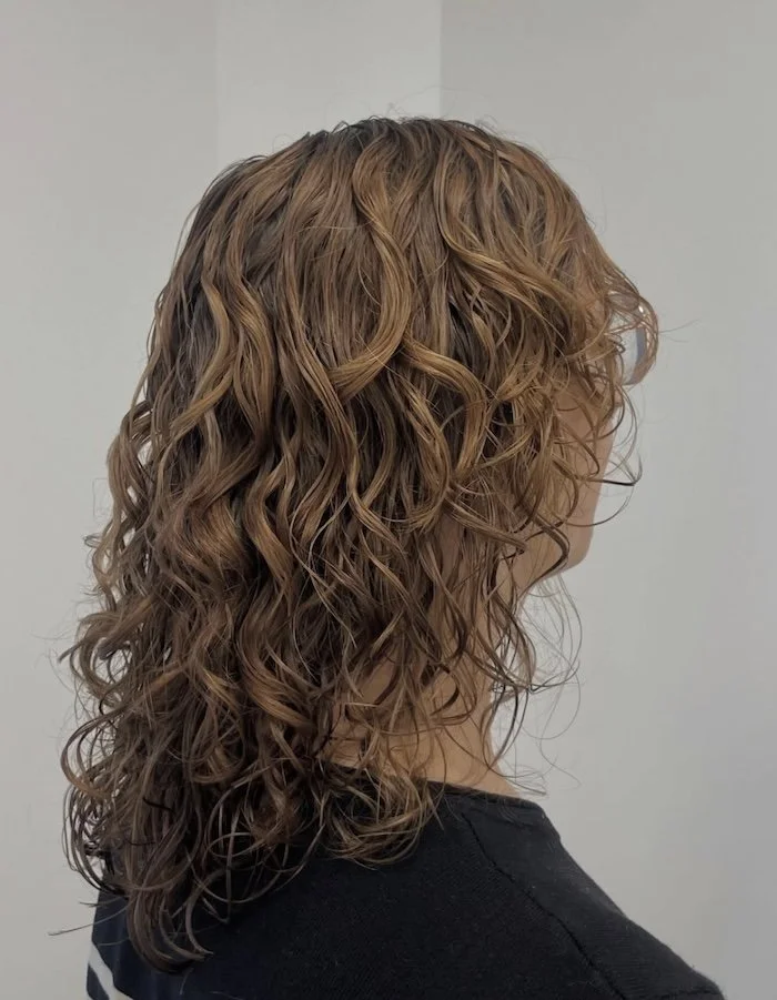 Side view of a woman with shoulder-length, curly, light brown hair.