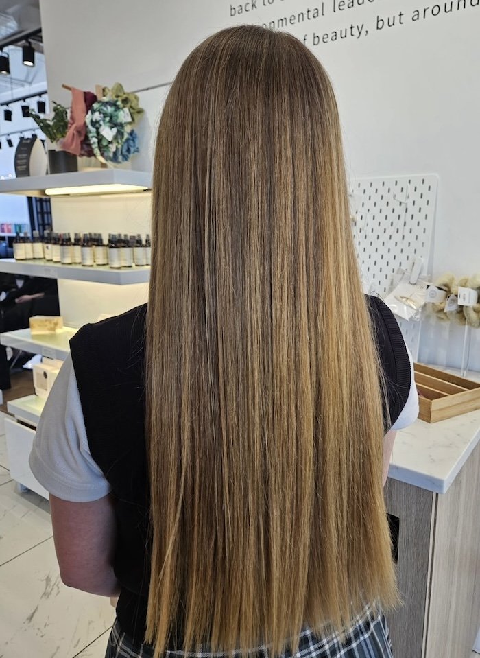 Back of a woman with long, straight, blonde hair in a store or salon.