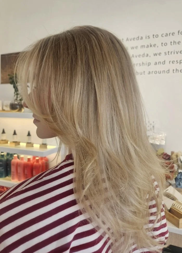 Woman with long, blonde, curly hair wearing a red and white striped shirt.
