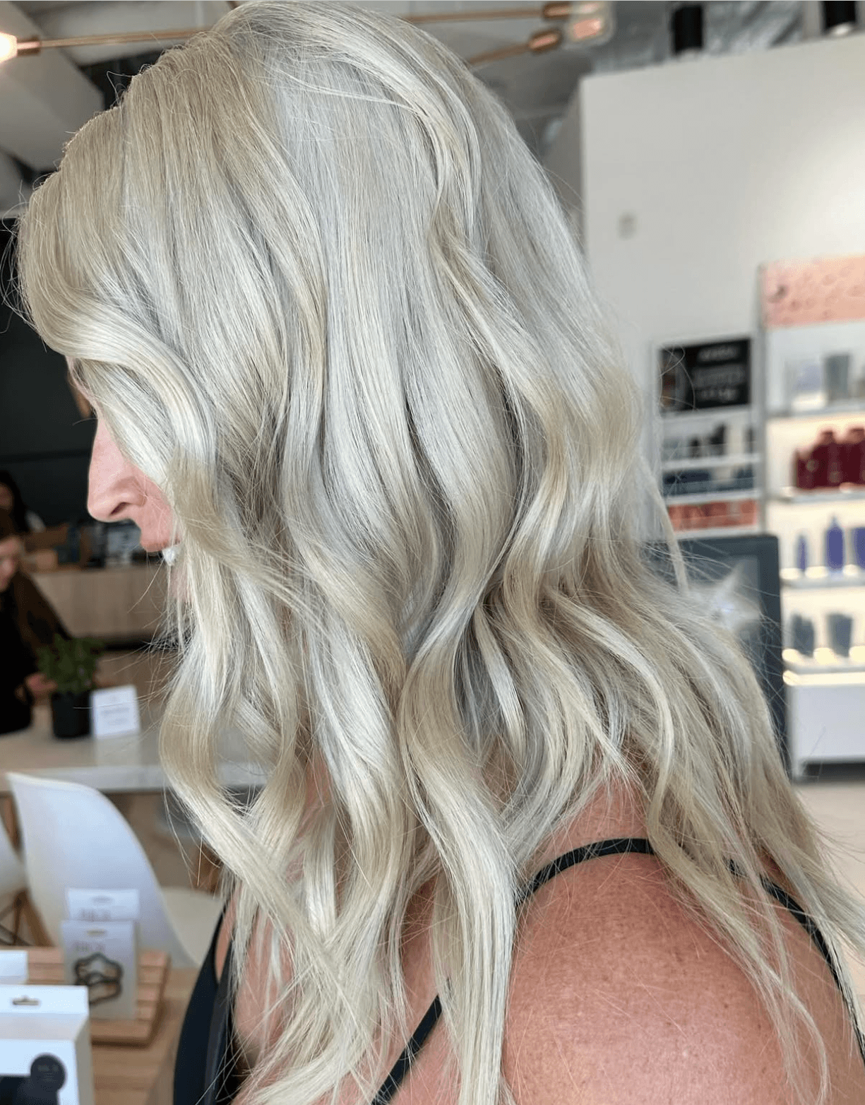 Side profile of a woman with long, wavy, platinum blonde hair in a store.