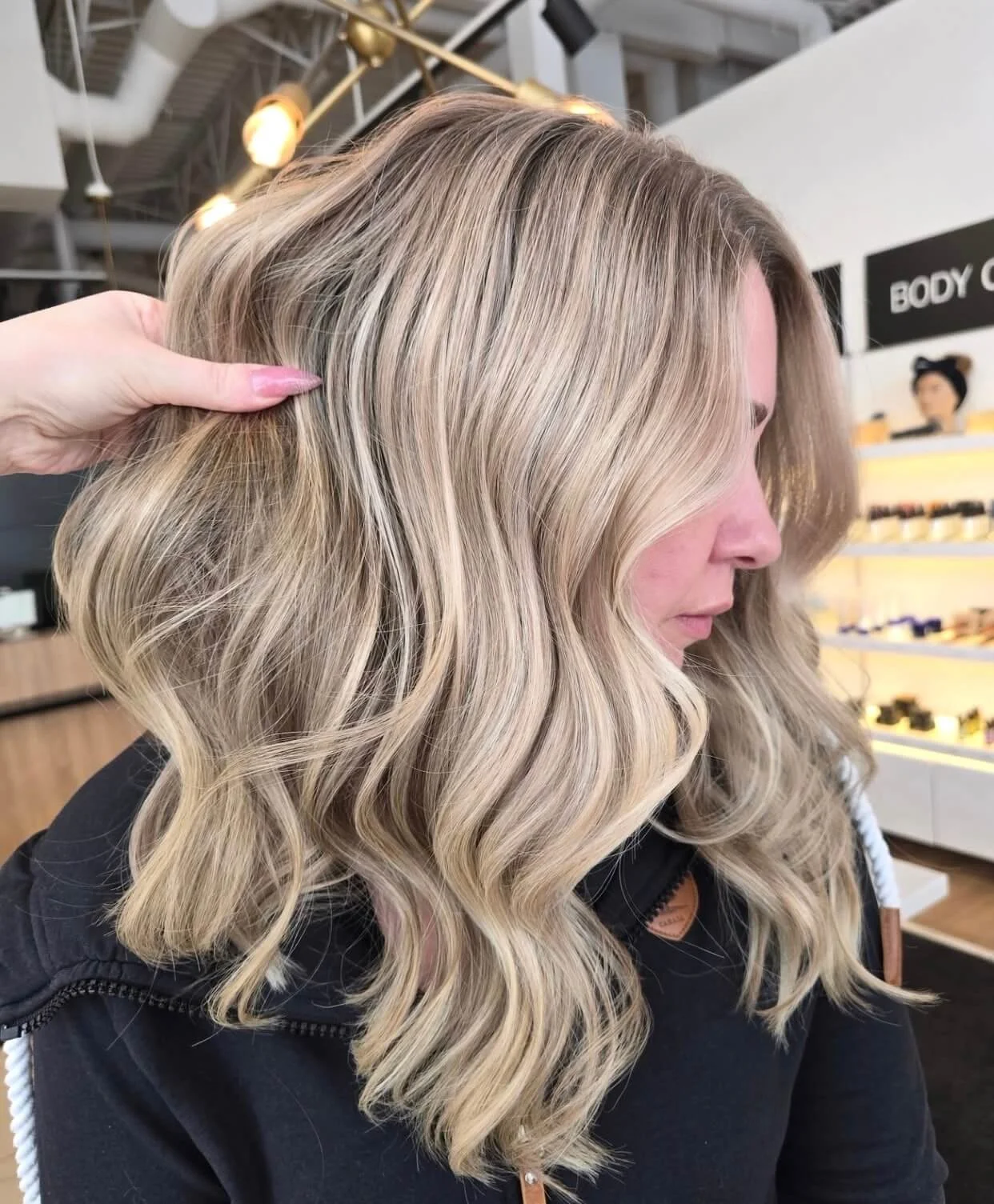 Close-up side view of a woman with long, wavy blonde hair, styled in a salon.