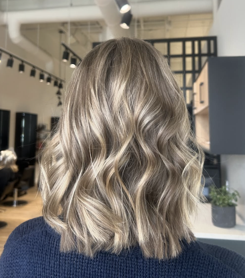 Woman with shoulder-length wavy blonde hair in a salon.