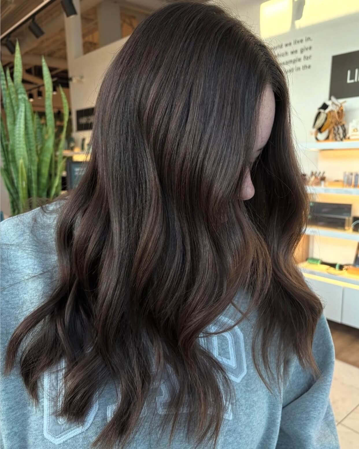 A woman with long, wavy, dark brown hair in a salon.