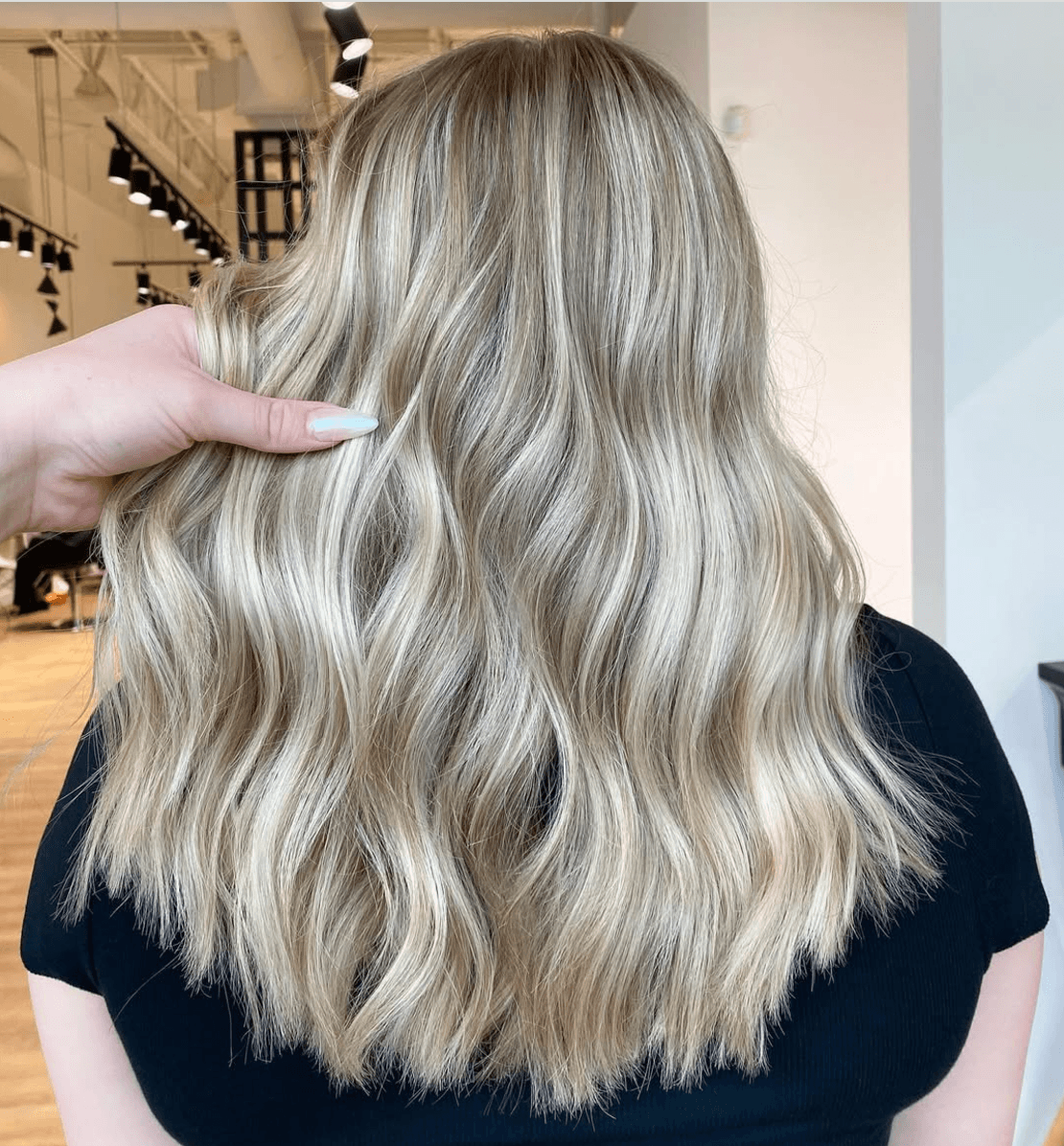Close-up of a woman with long, wavy, blonde hair in a salon.