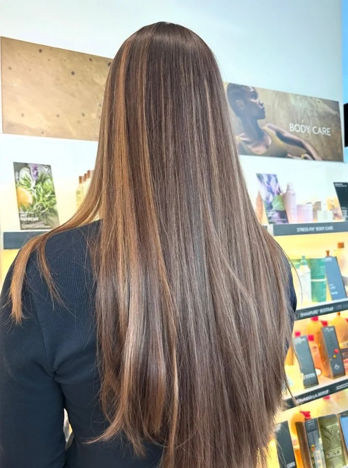 Back of a woman with long, straight, light brown hair in a store aisle.