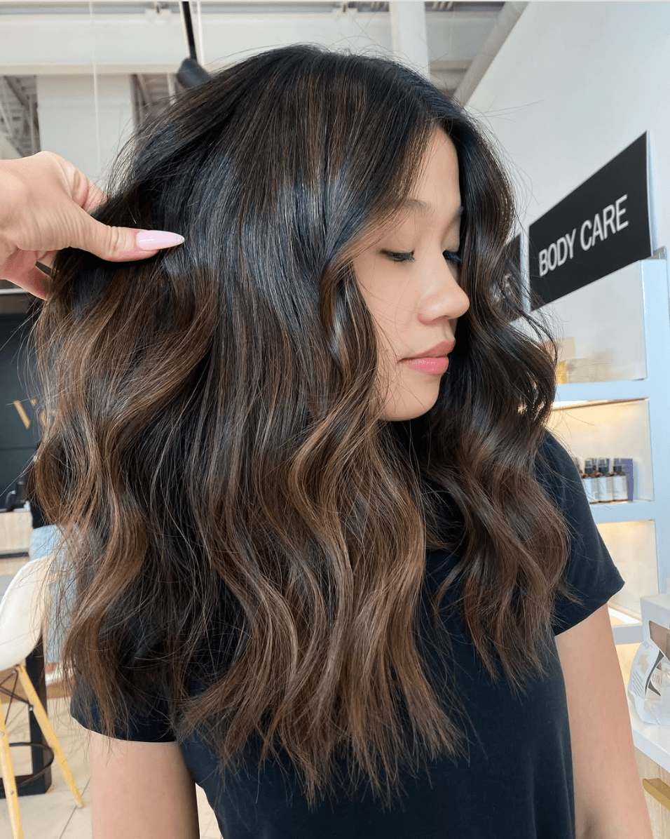 Woman with long, wavy brown hair in a salon.