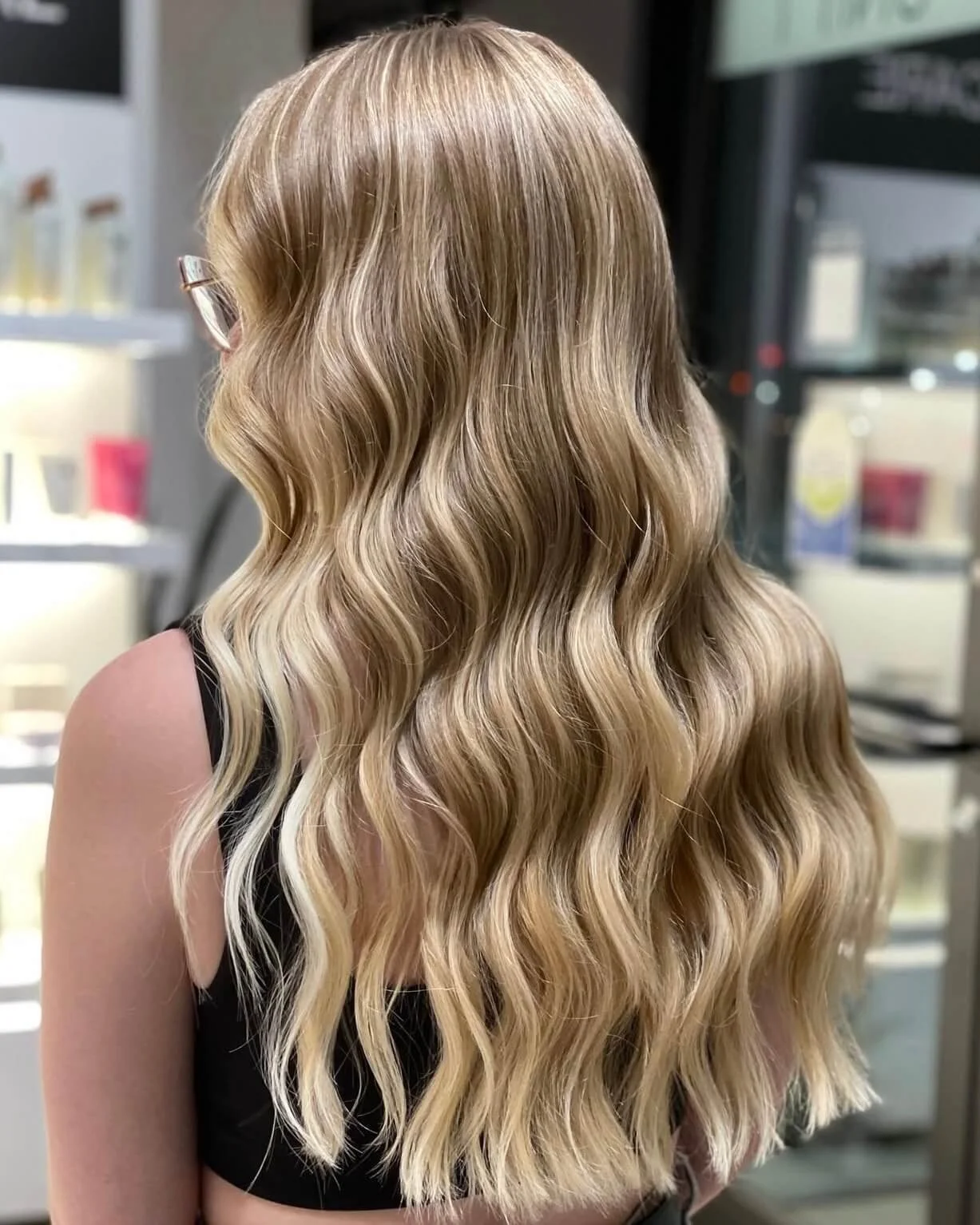 Back view of a woman with long, wavy blonde hair.