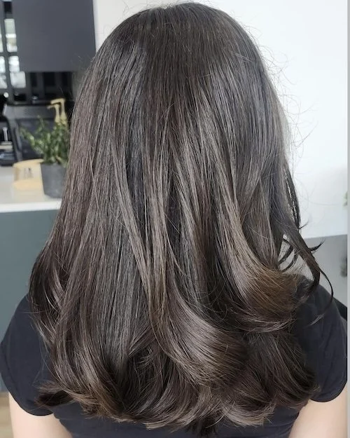 Back view of a woman with long, wavy brown hair.