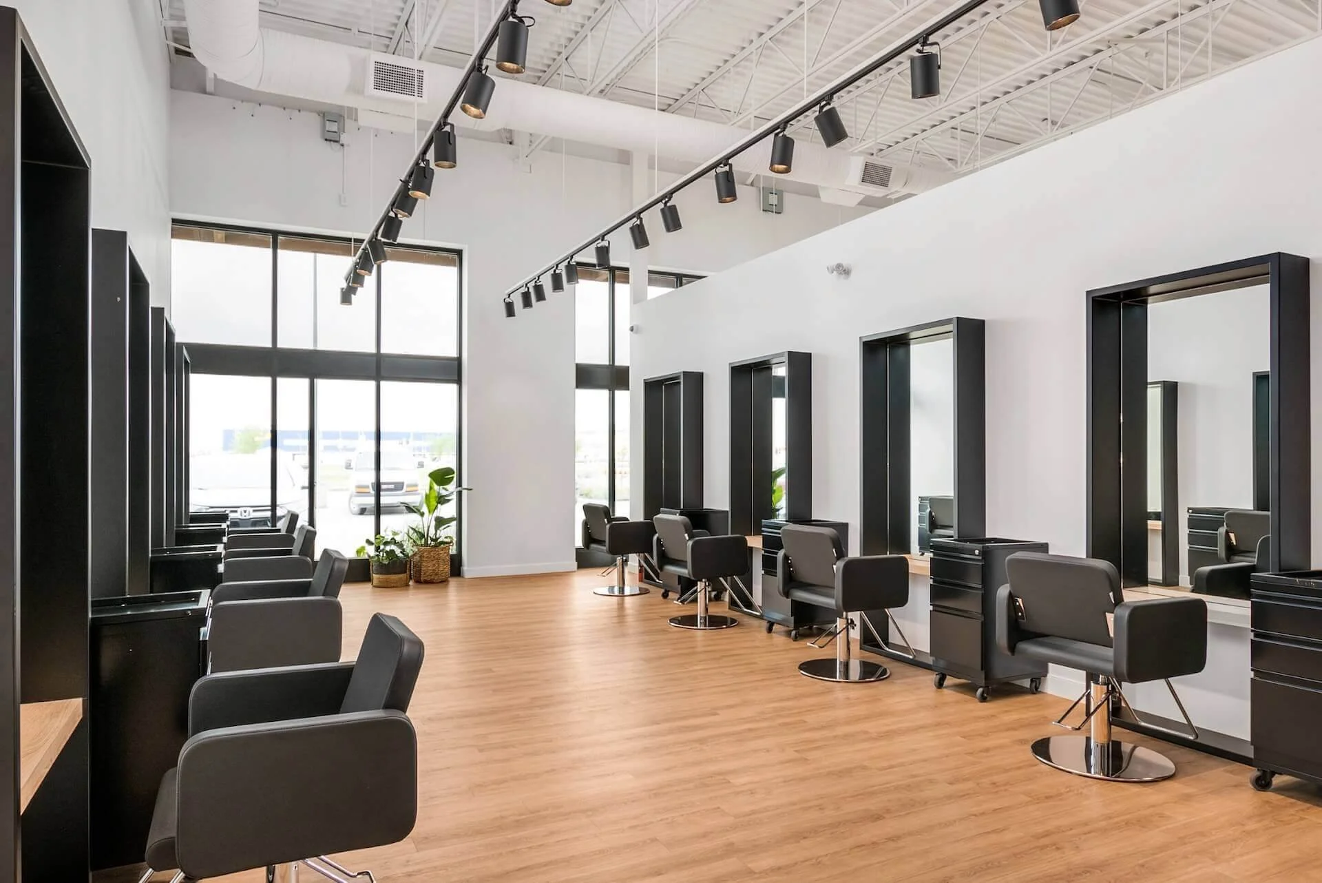 Interior of a verde salon with multiple styling stations, black chairs, mirrors, and a large window providing natural light.