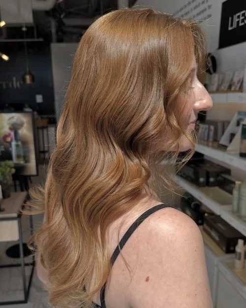 Profile of a woman with long, wavy, red hair in a retail store.