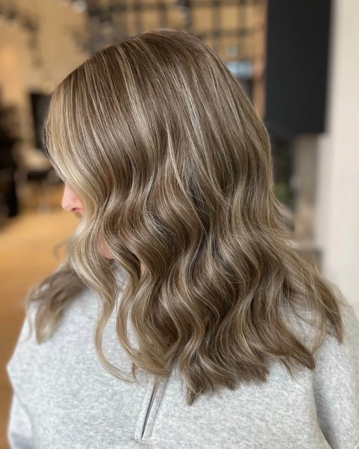 Woman with shoulder-length wavy light brown hair, with subtle blonde highlights.