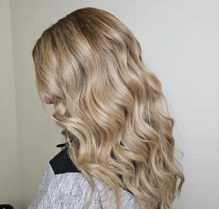 Side view of a woman with blonde, wavy, shoulder-length hair.