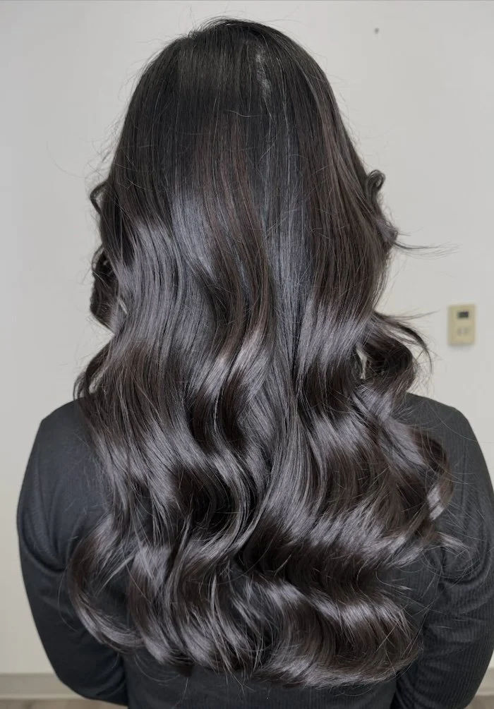 Back view of a woman with long, wavy, dark brown or black hair
