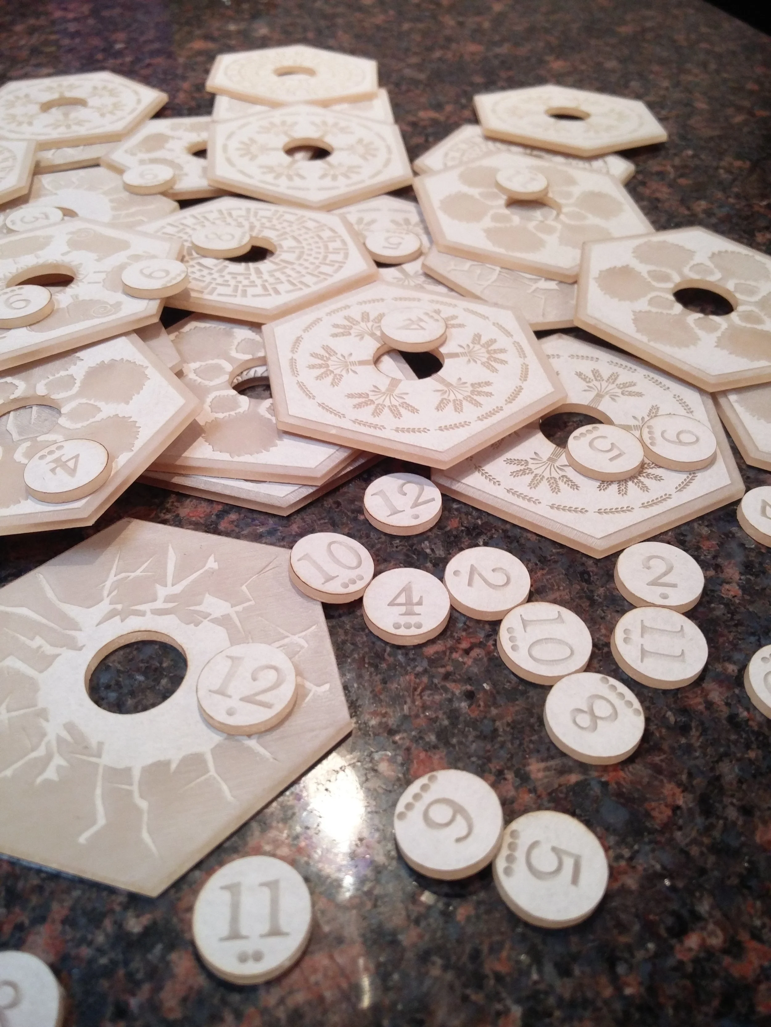  The font on the numbered tokens was chosen so they can be easily read regardless of thier orientation.  The dots beneath the numbers represent the probability of that number being rolled with two 6-sided dice. The more dots, the greater the probabil