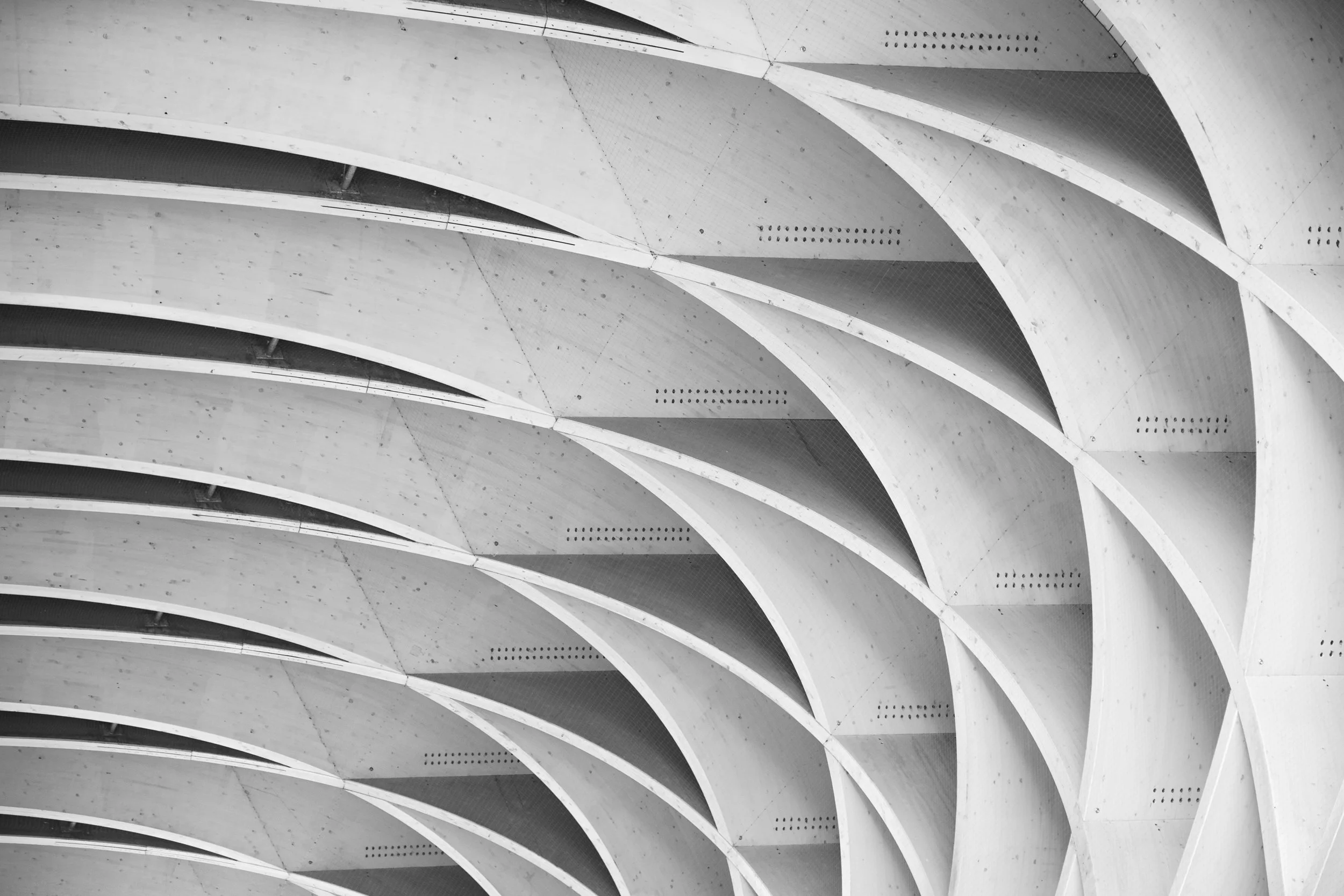 Close-up view of an abstract architectural structure with curved concrete beams forming a repetitive pattern.