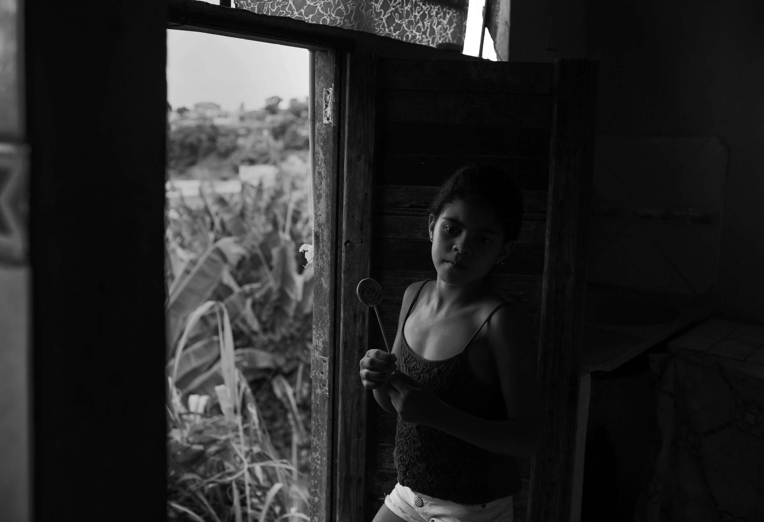  Temperatures soar during the summer in northeast Brazil, and many homes cannot afford air conditioning. Here, Evellyn Mendes Santos, age 9, stands near a door that stays open in attempt to keep the family's home somewhat cool. But without screens on