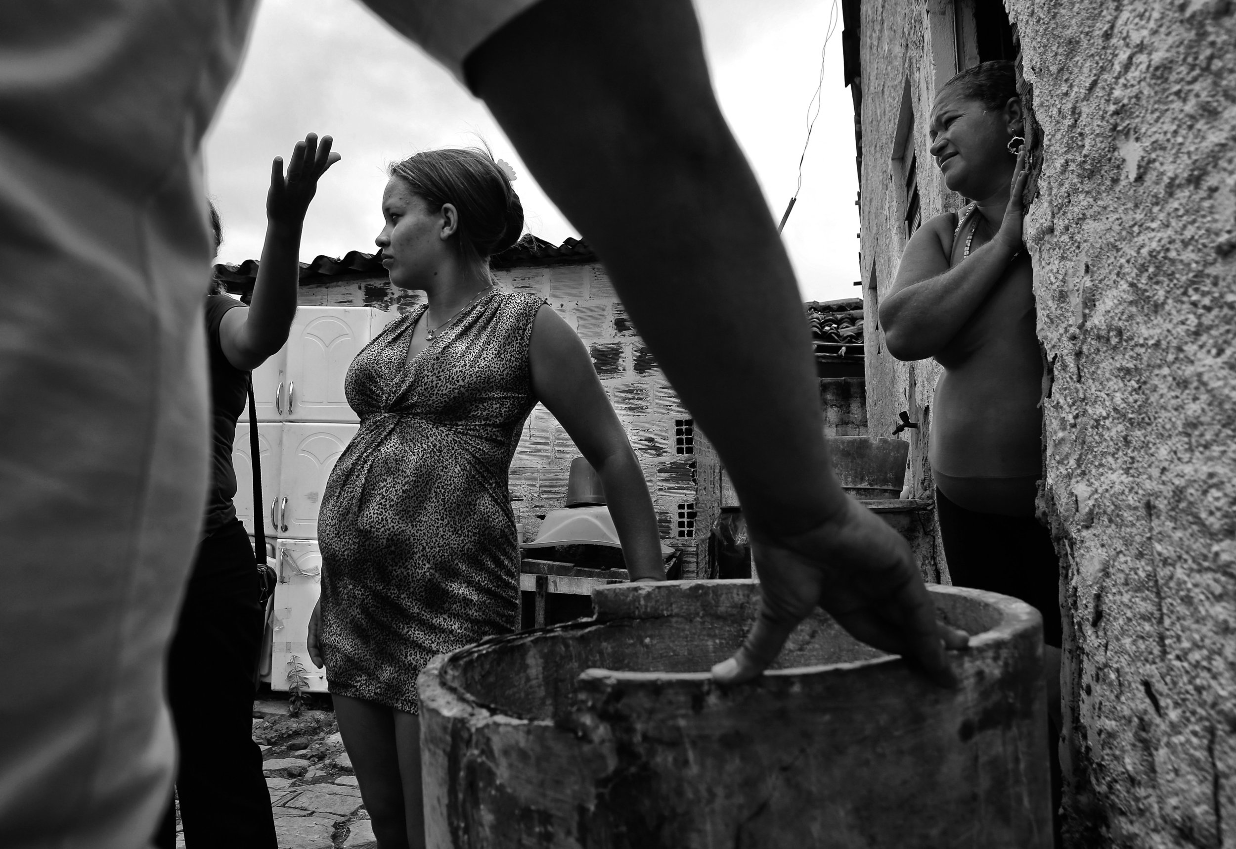  Behind their home, Carla de Sousa, who is pregnant, left, and her mother, Maria de Sousa, listen as mosquito control agents give tips on how to prevent mosquitoes around their home. An agent drew a sample of water being stored in a broken washing ma