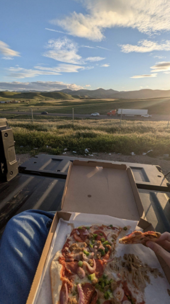 Author eating pizza on the back of a truck