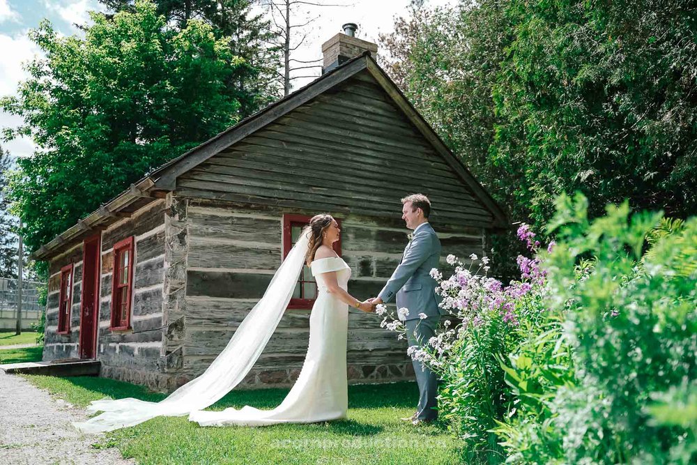 134-bride-and-groom-holding-hand-in-front-of-log-cabin-stouffville-museum.jpg