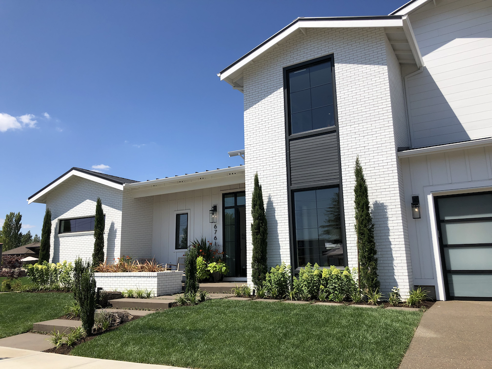 I have to admit that Italian cypress, modern garage doors, and large walls of white brick did not immediately make me think of a farmhouse.