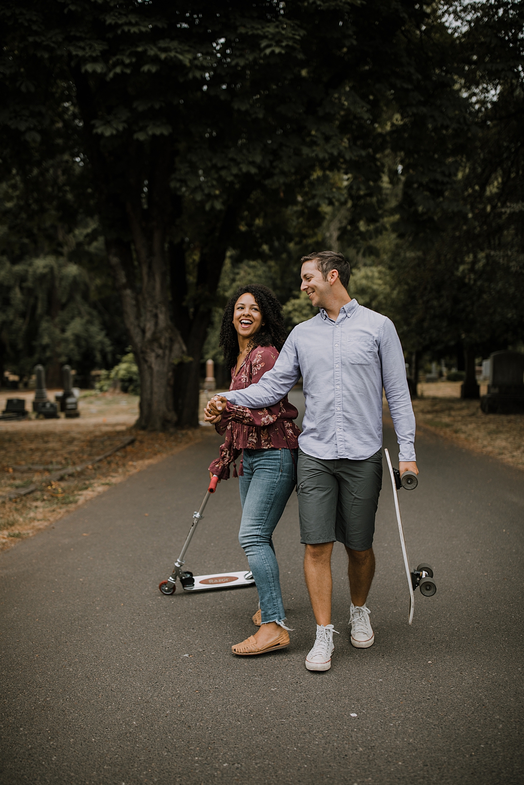 couple riding scooters in portland oregon, portland oregon engagements, portland oregon cemetery walk, riding scooters for your engagement session, downtown portland