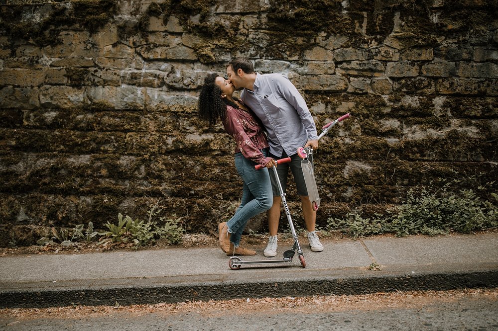 couple riding scooters in portland oregon, portland oregon engagements, portland oregon cemetery walk, riding scooters for your engagement session, downtown portland