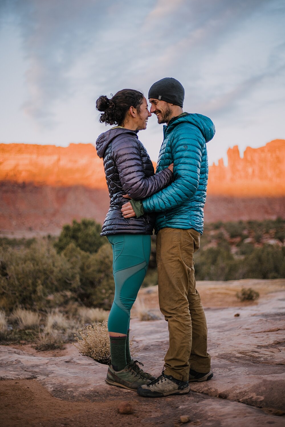 couple hiking through indian creek near monticello utah, indian creek climbing area, canyonlands national park, moab utah engagements, sunrise in moab utah