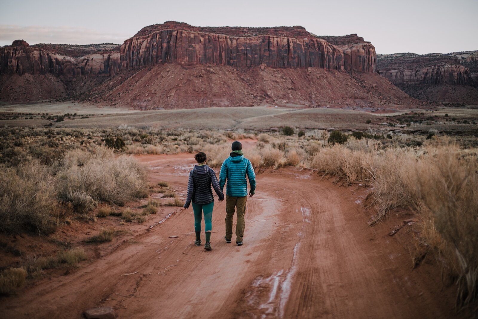 couple hiking through indian creek near monticello utah, indian creek climbing area, canyonlands national park, moab utah engagements, sunrise in moab utah