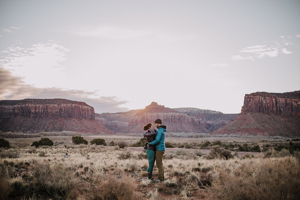 couple hiking through indian creek near monticello utah, indian creek climbing area, canyonlands national park, moab utah engagements, sunrise in moab utah