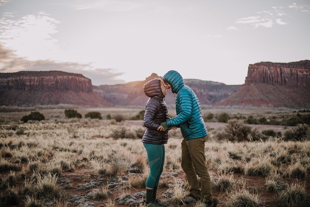 couple hiking through indian creek near monticello utah, indian creek climbing area, canyonlands national park, moab utah engagements, sunrise in moab utah