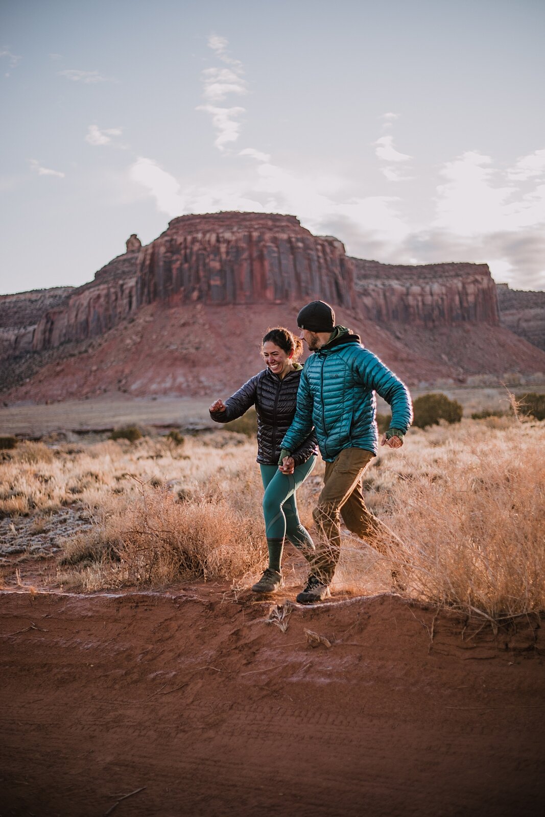 couple running through indian creek near monticello utah, indian creek climbing area, canyonlands national park, moab utah engagements, sunrise in moab utah