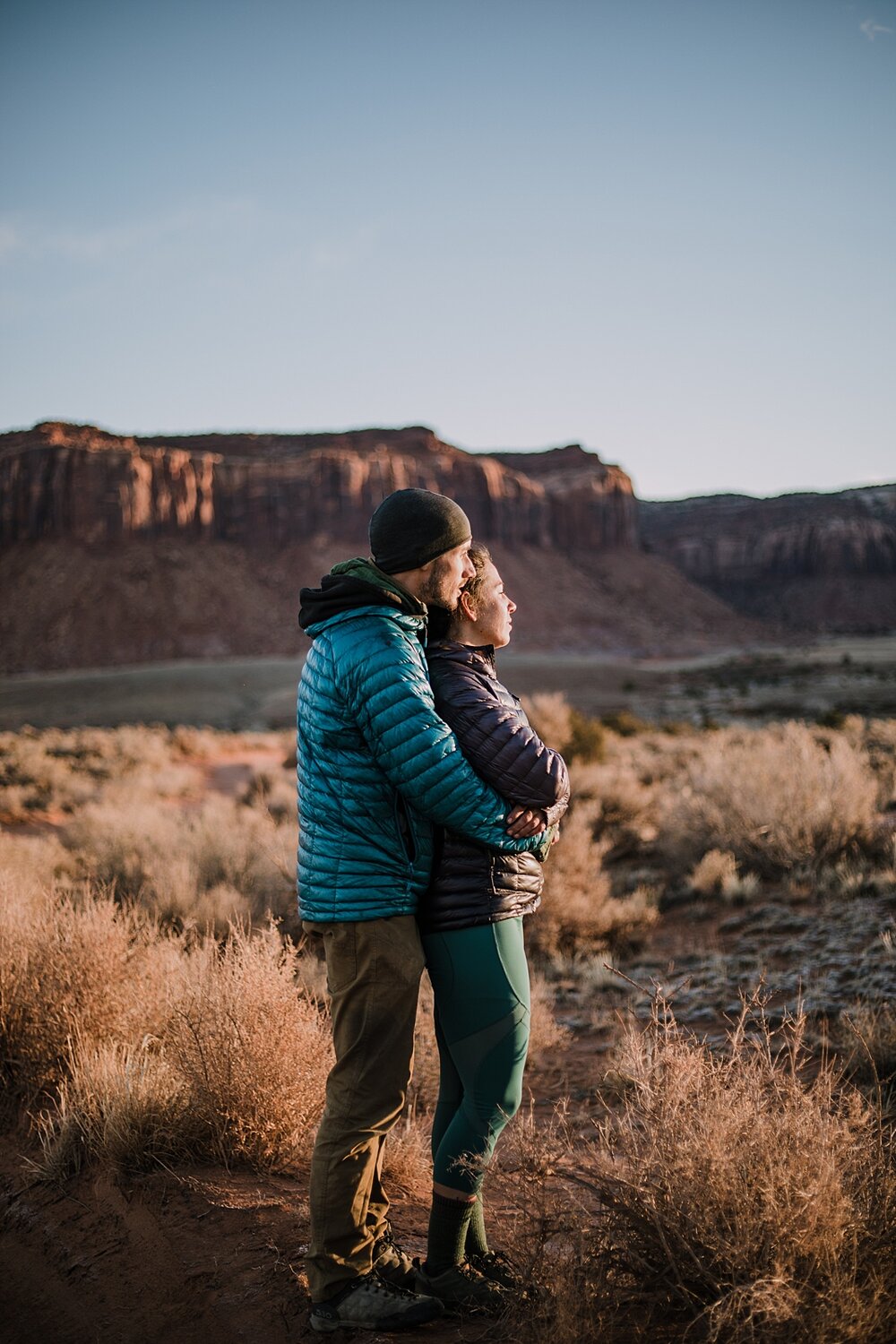 couple hiking through indian creek near monticello utah, indian creek climbing area, canyonlands national park, moab utah engagements, sunrise in moab utah