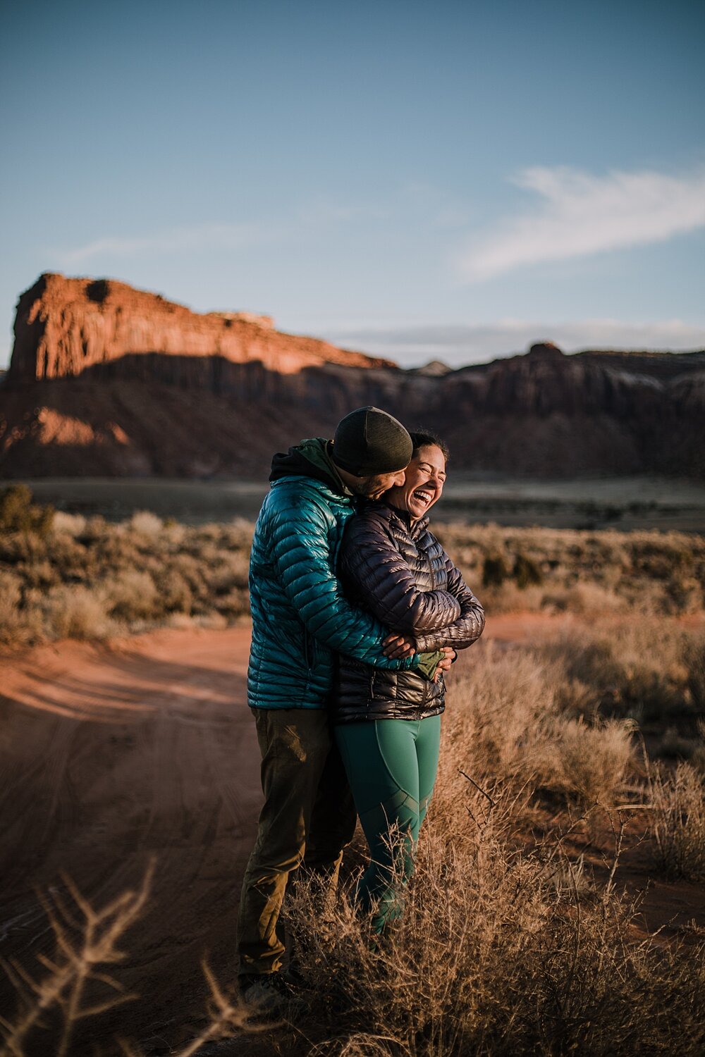 couple hiking through indian creek near monticello utah, indian creek climbing area, canyonlands national park, moab utah engagements, sunrise in moab utah