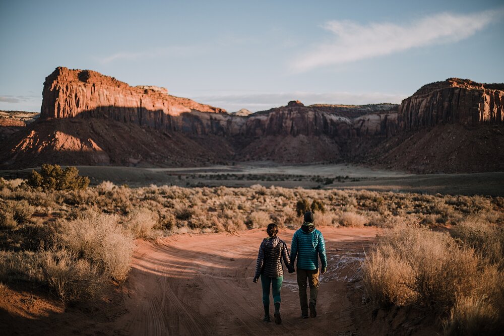 couple hiking through indian creek near monticello utah, indian creek climbing area, canyonlands national park, moab utah engagements, sunrise in moab utah