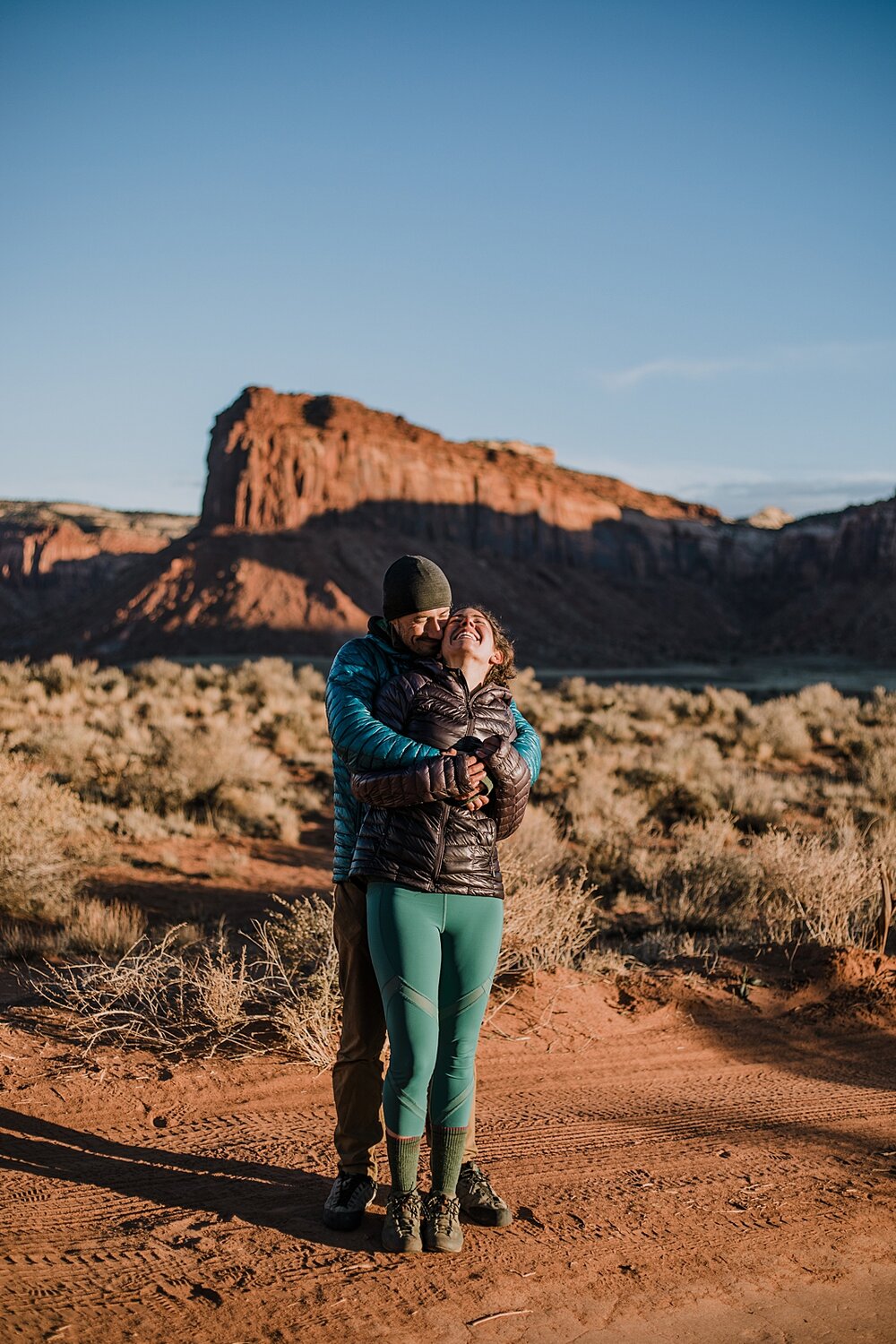 couple hiking through indian creek near monticello utah, indian creek climbing area, canyonlands national park, moab utah engagements, sunrise in moab utah